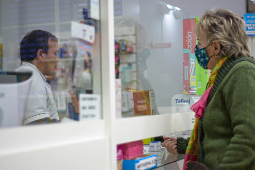Realistic scene of a traveler walking through an international pedestrian border toward a pharmacy.