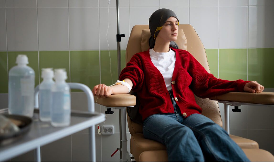 Young female cancer patient wearing a cold cap and receiving intravenous chemotherapy infusion for Chronic Myeloid Leukemia (CML) in a hospital oncology unit