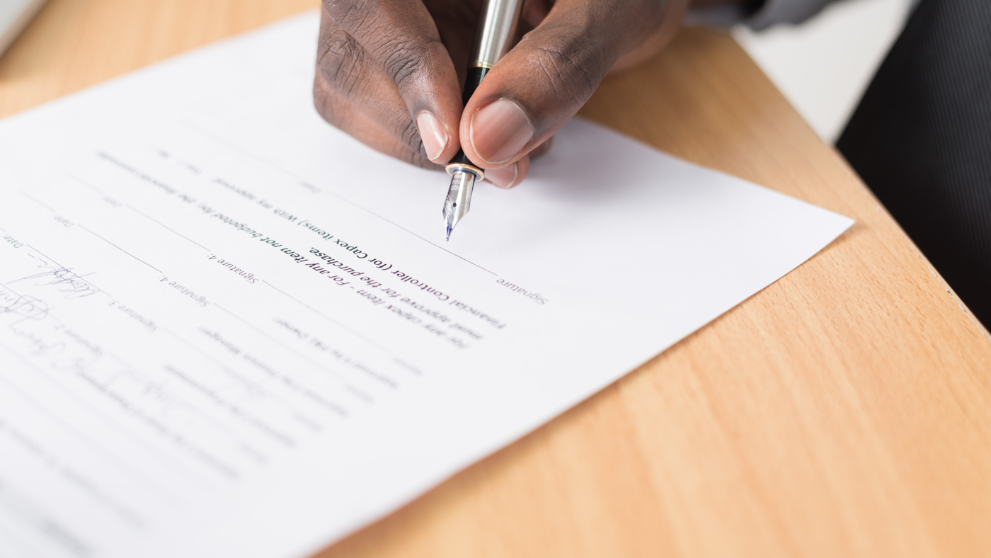 A person reviewing and signing documents at a desk, representing prescription and compliance paperwork