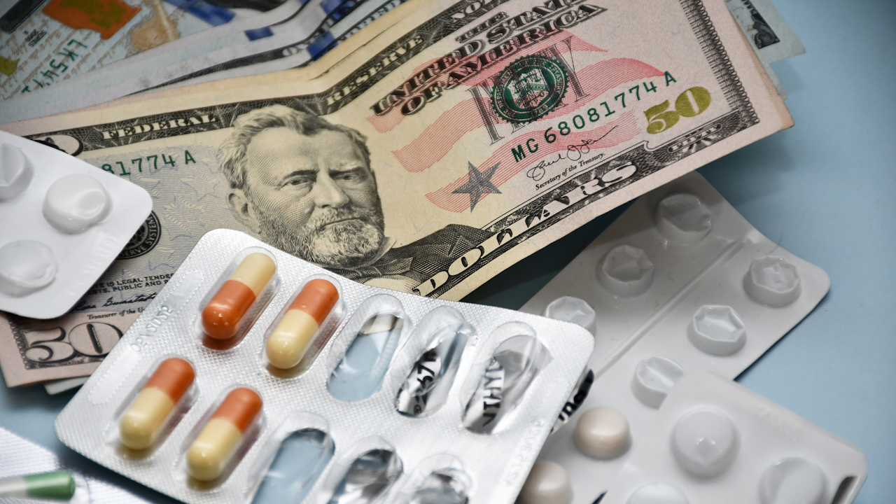 Prescription pills beside U.S. dollars, showing the out-of-pocket costs the Medicare Part D 2026 cap does not fully close